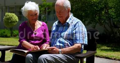 积极的高加索老年夫妇在<strong>养老院</strong>花园观看相册的正面景色
